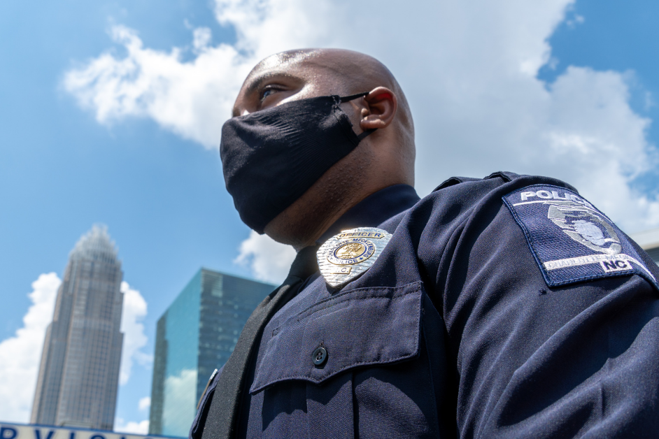 Charlotte-Mecklenburg Police Department officer wears a mask in front of the Charlotte skyline