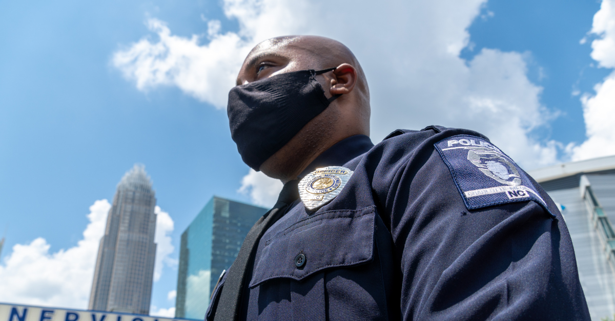 Charlotte-Mecklenburg Police Department officer wears a mask in front of the Charlotte skyline